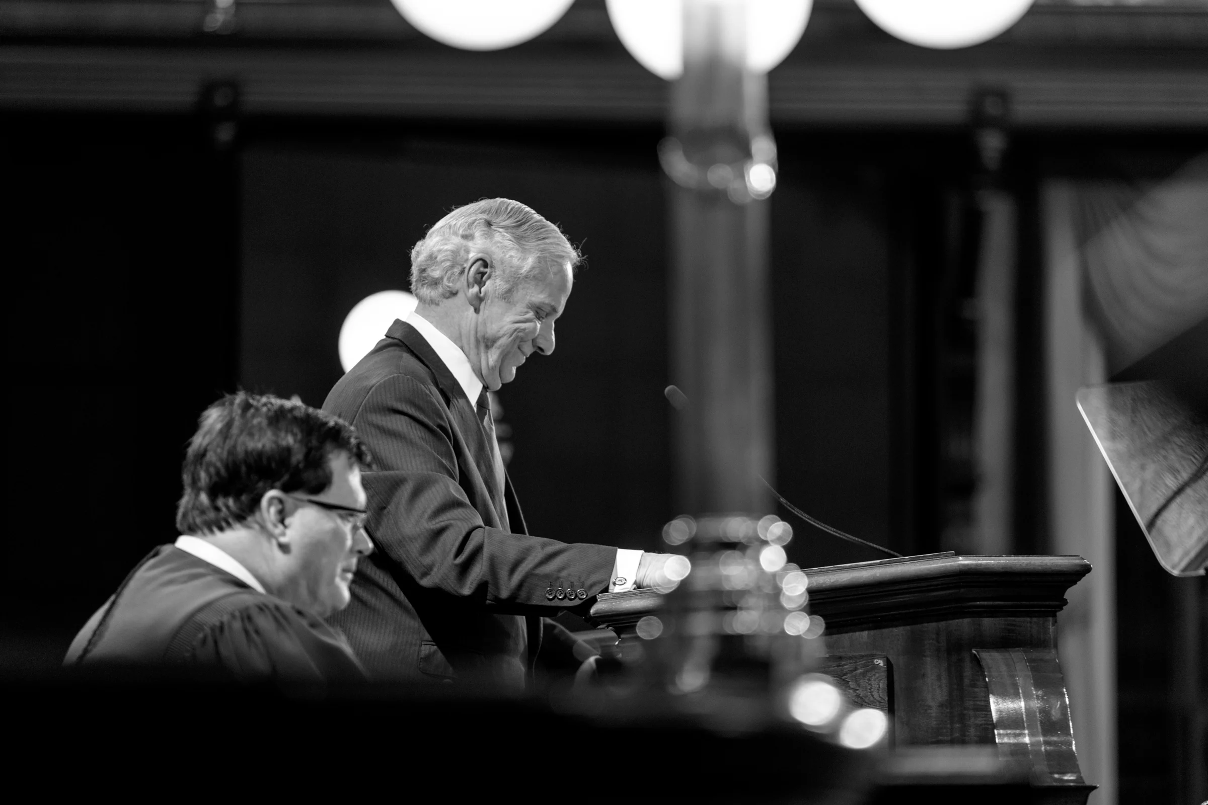 Black-and-white candid portrait at a lectern