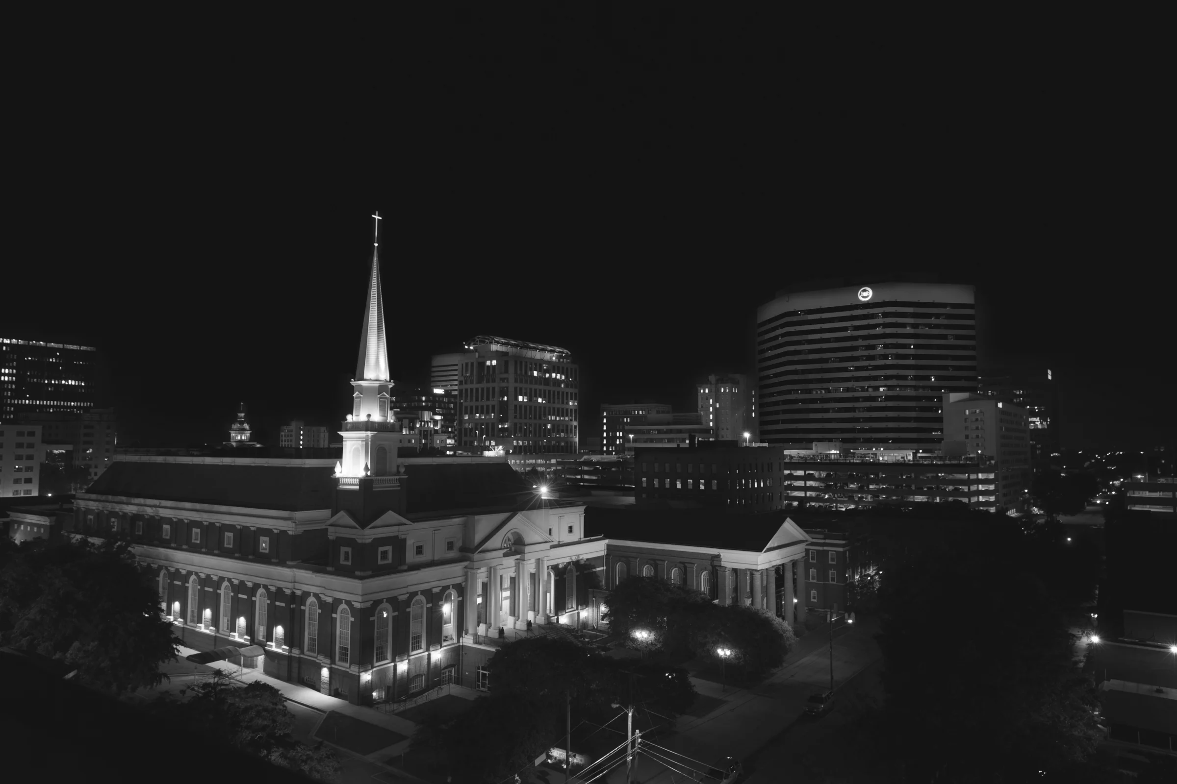 Nighttime black-and-white aerial of downtown Columbia with a church in the foreground