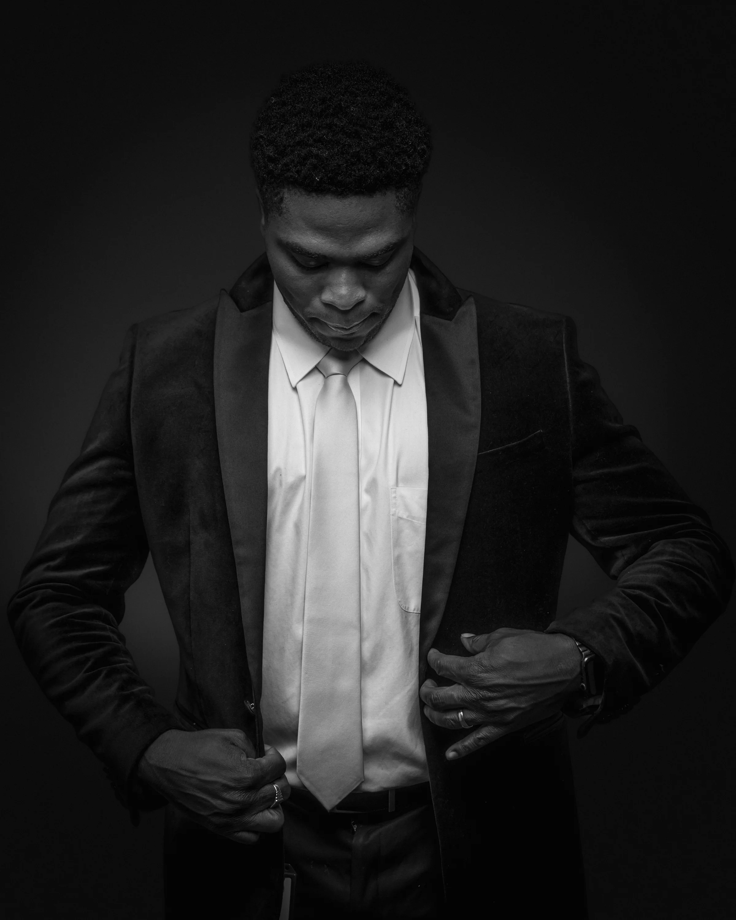 Black-and-white formal portrait of a man adjusting his jacket